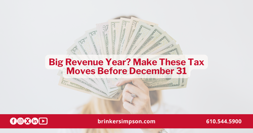 Business owner holding a fan of cash, representing year-end tax planning