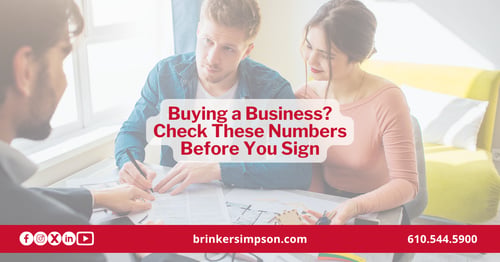Buyers and an advisor reviewing financial documents before signing a purchase agreement